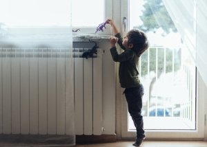 Enfant qui joue sur un radiateur électrique de son logement